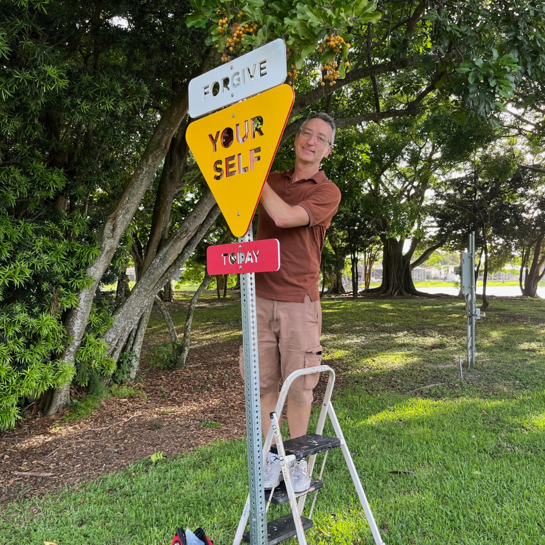 Artist with Forgive Yourself Sign