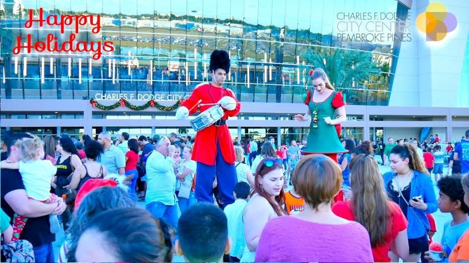 Snowfest crowd shot in front of City Center with holiday decorations and stilt walkers